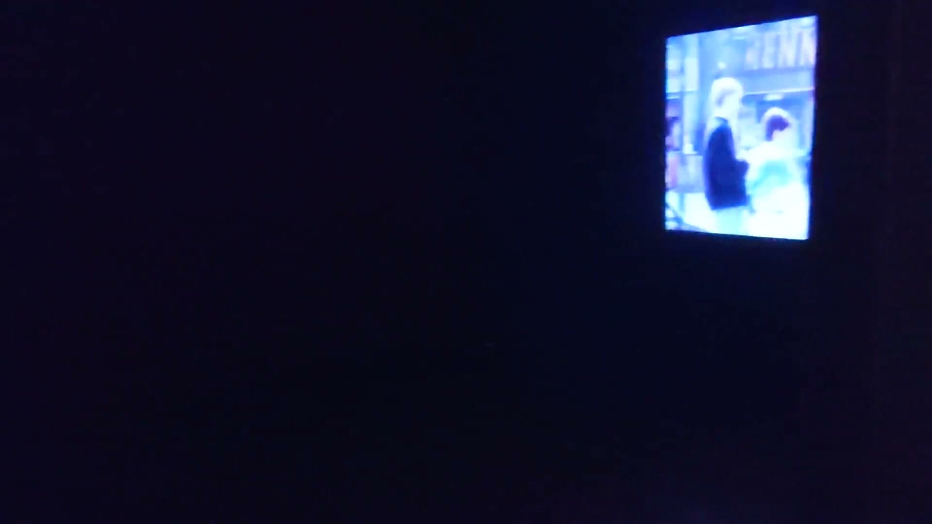 Dark room with single screen showing film