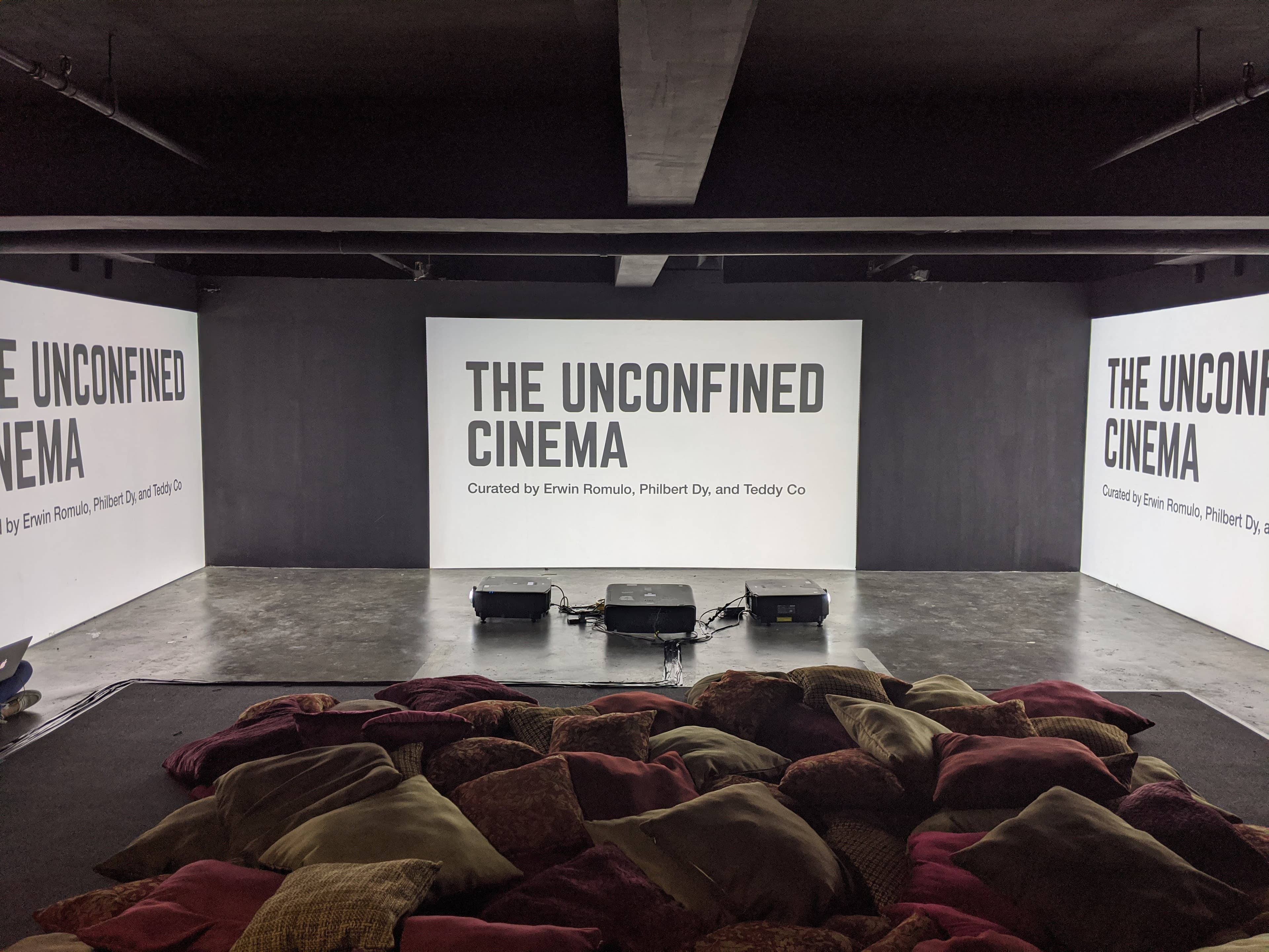 Triptych projection showing The Unconfined Cinema title screens