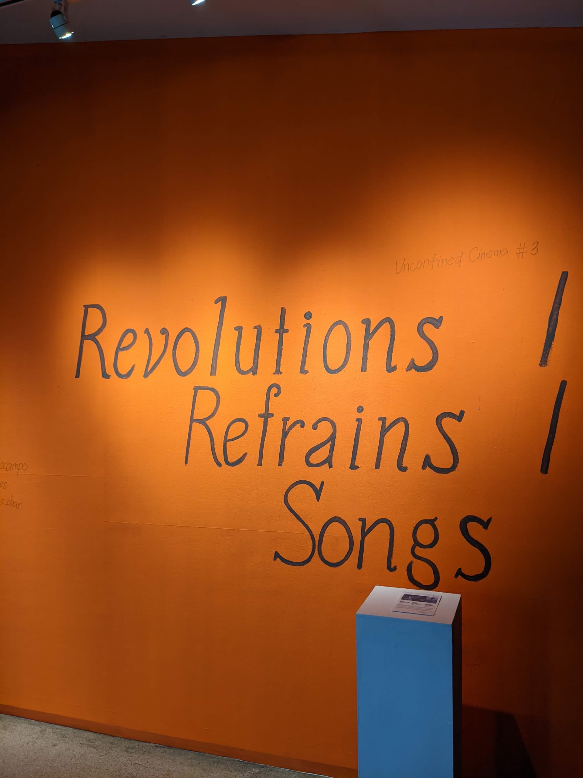 Orange wall with Revolutions, Refrains, Songs handwritten title
